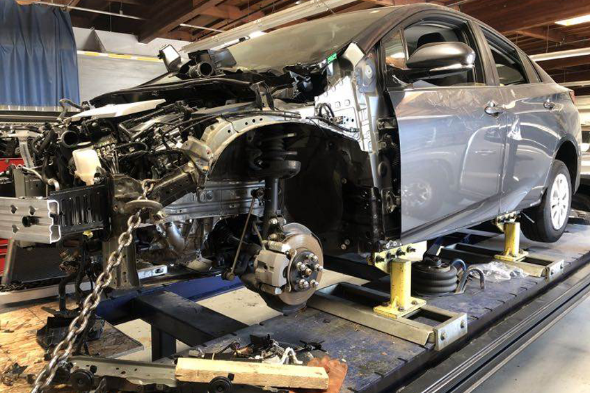 New-frame-Repair Auto body repairs. Repairman mechanic worker plastering automobile car body by plaster in garage workshop